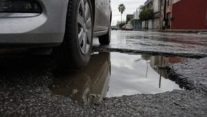 Llanta de un auto junto a un bache lleno de agua en una calle mojada de México