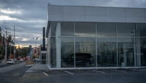 Agencia de autos con las luces apagadas y el estacionamiento vacío al anochecer