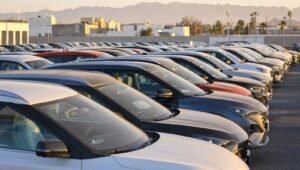 Filas de autos nuevos estacionados en el patio de una agencia automotriz al atardecer