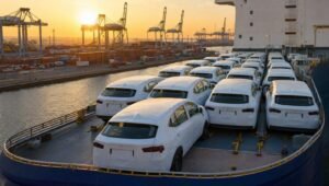 Sedanes nuevos cubiertos con plastico protector sobre un buque de carga en un puerto al atardecer